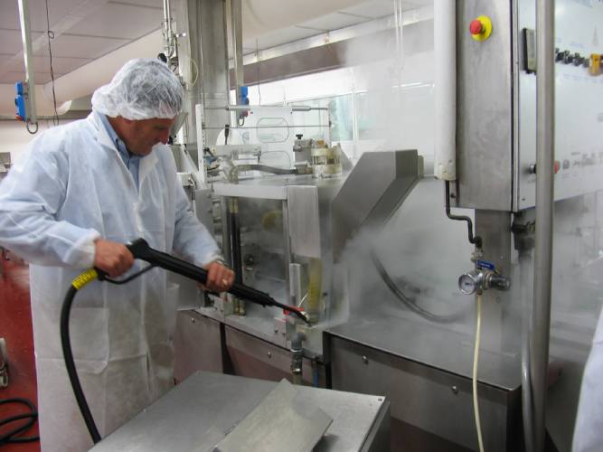 The Hot Water Pressure Washer being used in an industrial factory setting, showcasing its effectiveness in heavy-duty cleaning.