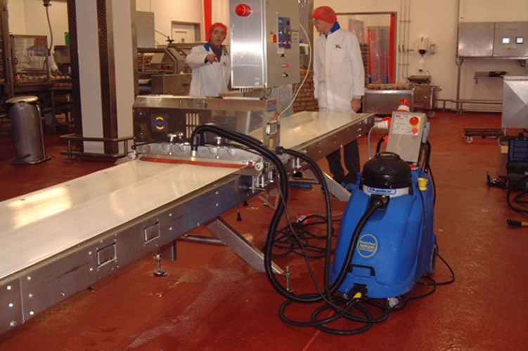 Image illustrating the thorough cleaning of conveyor belts in a food and beverage manufacturing environment with specialised equipment.