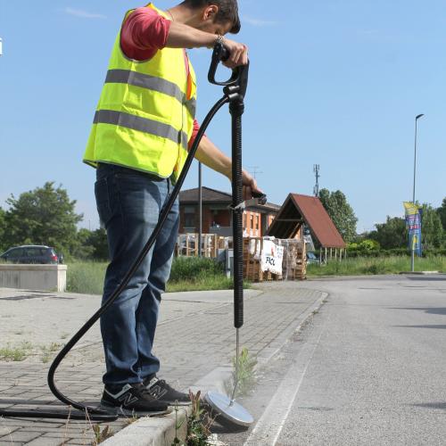 Commercial steam weed killer in use on a roadside, showcasing efficient and eco-friendly weed control. This method provides thorough weed removal without chemicals, suitable for maintaining cleanliness in public and commercial areas.