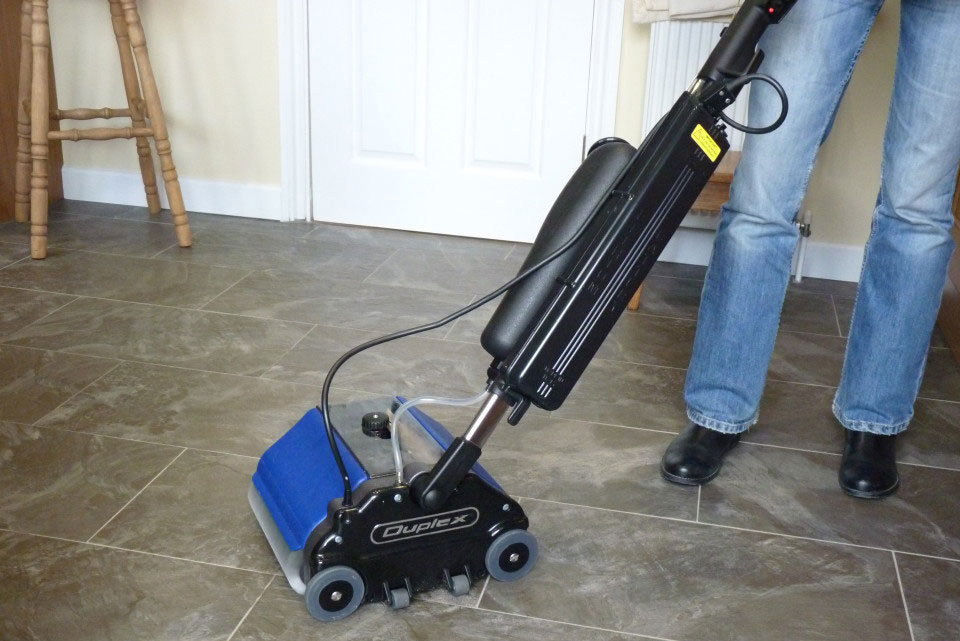 Duplex Lithium Floor Scrubber in use on a tiled floor, demonstrating its versatility for various environments.