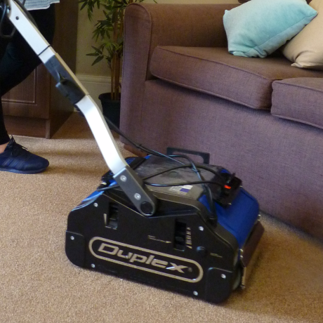 Using a commercial floor cleaner to steam clean carpets in a youth hostel room.
