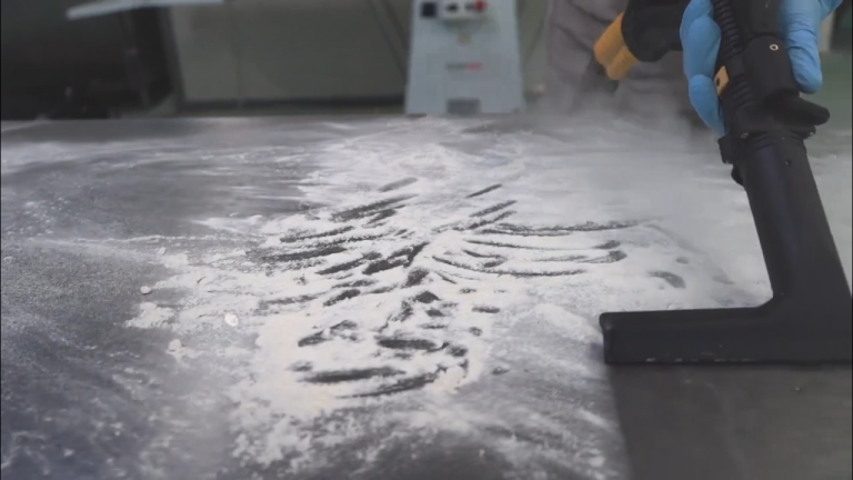 Steam cleaning dry residue from a stainless steel food preparation surface.