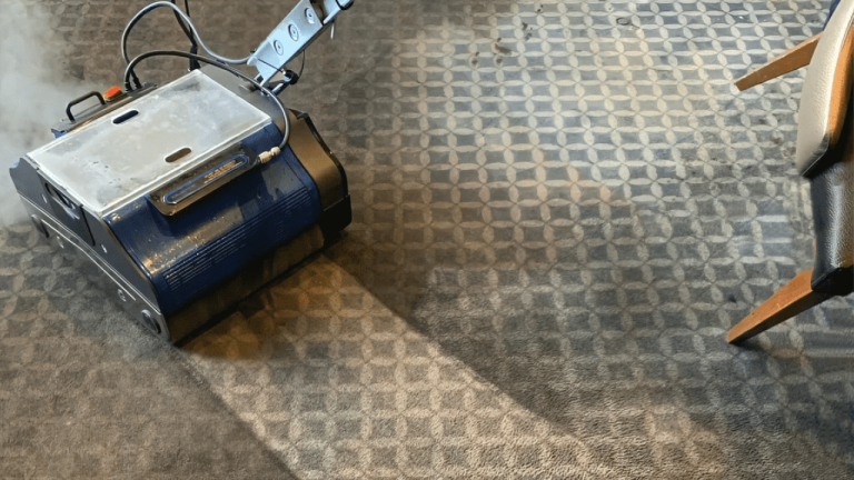 Commercial grade carpet cleaning equipment cleaning grey commercial carpet with visible contrast between cleaned and uncleaned sections.