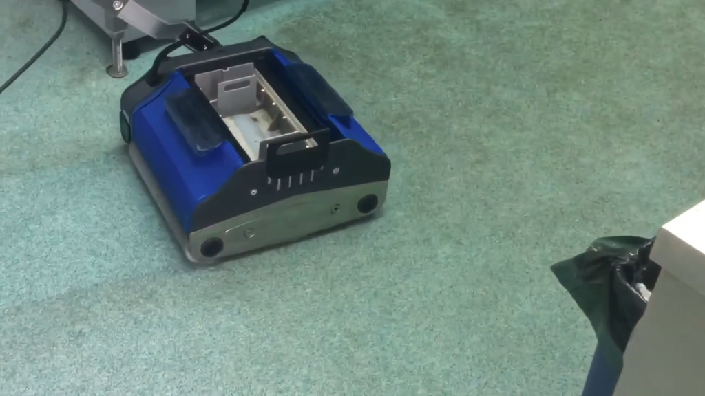 Commercial floor cleaning machine working on patterned carpet in a public facility.
